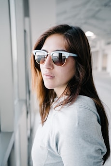 A stylish woman wearing an oversized hoodie, standing in a minimalist urban setting with soft natural lighting.