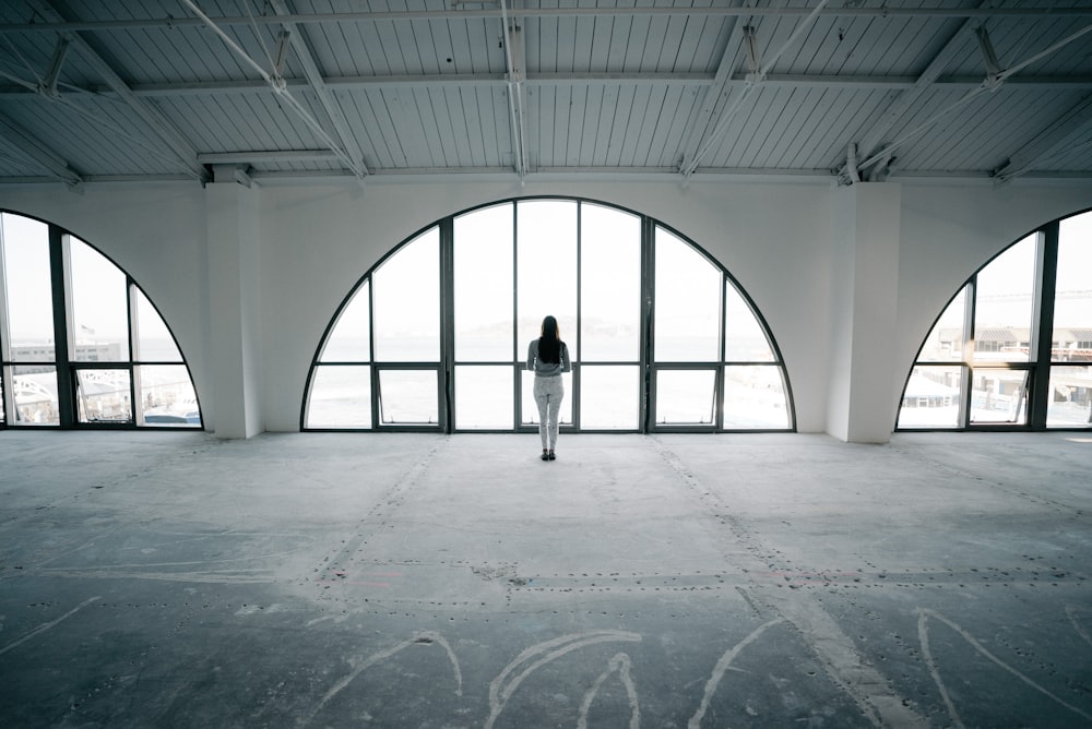 landscape photography of woman standing in front of glass window
