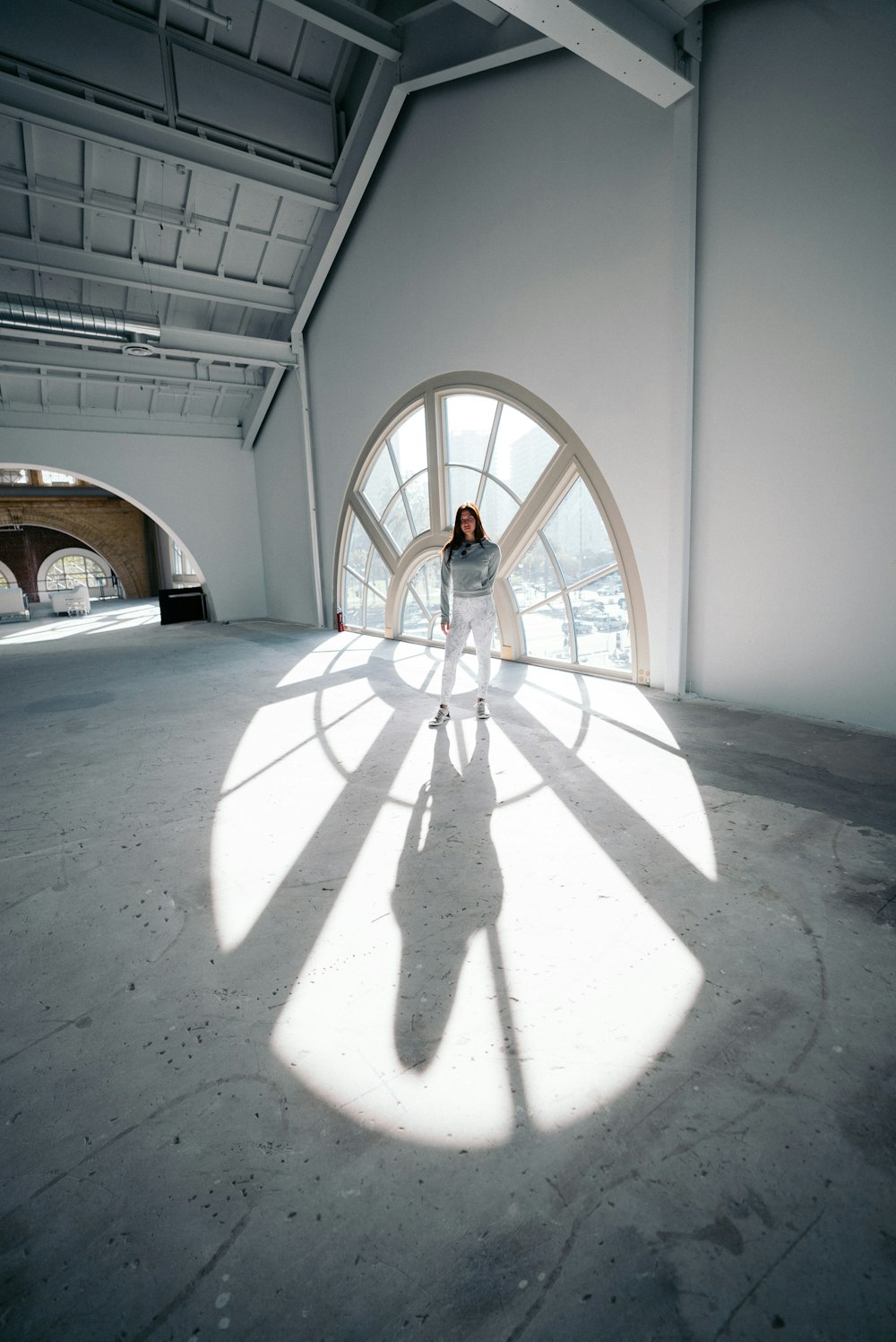 mulher em pé perto da janela de vidro de um edifício vazio