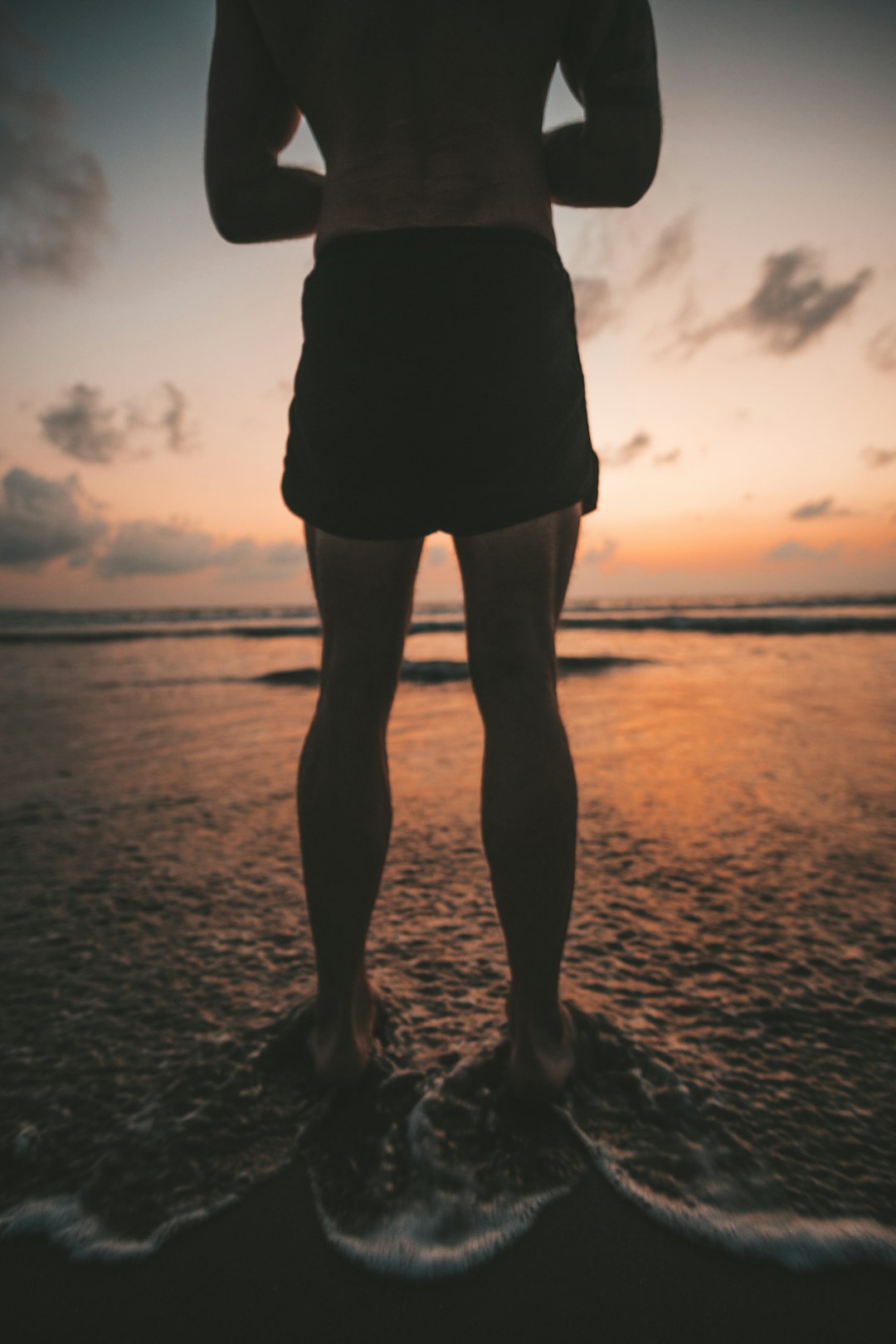 man wearing black shorts standing on the seashore