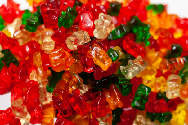 A vibrant display of gummy bears in various bright colors under soft lighting.