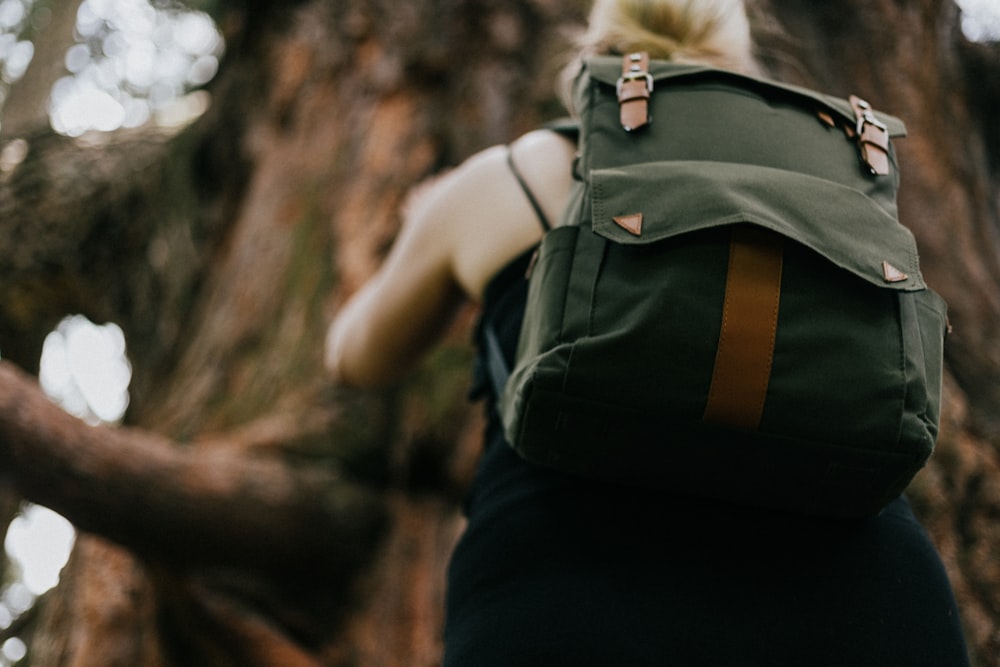 Mädchen mit grünem Rucksack, der auf Baum klettert