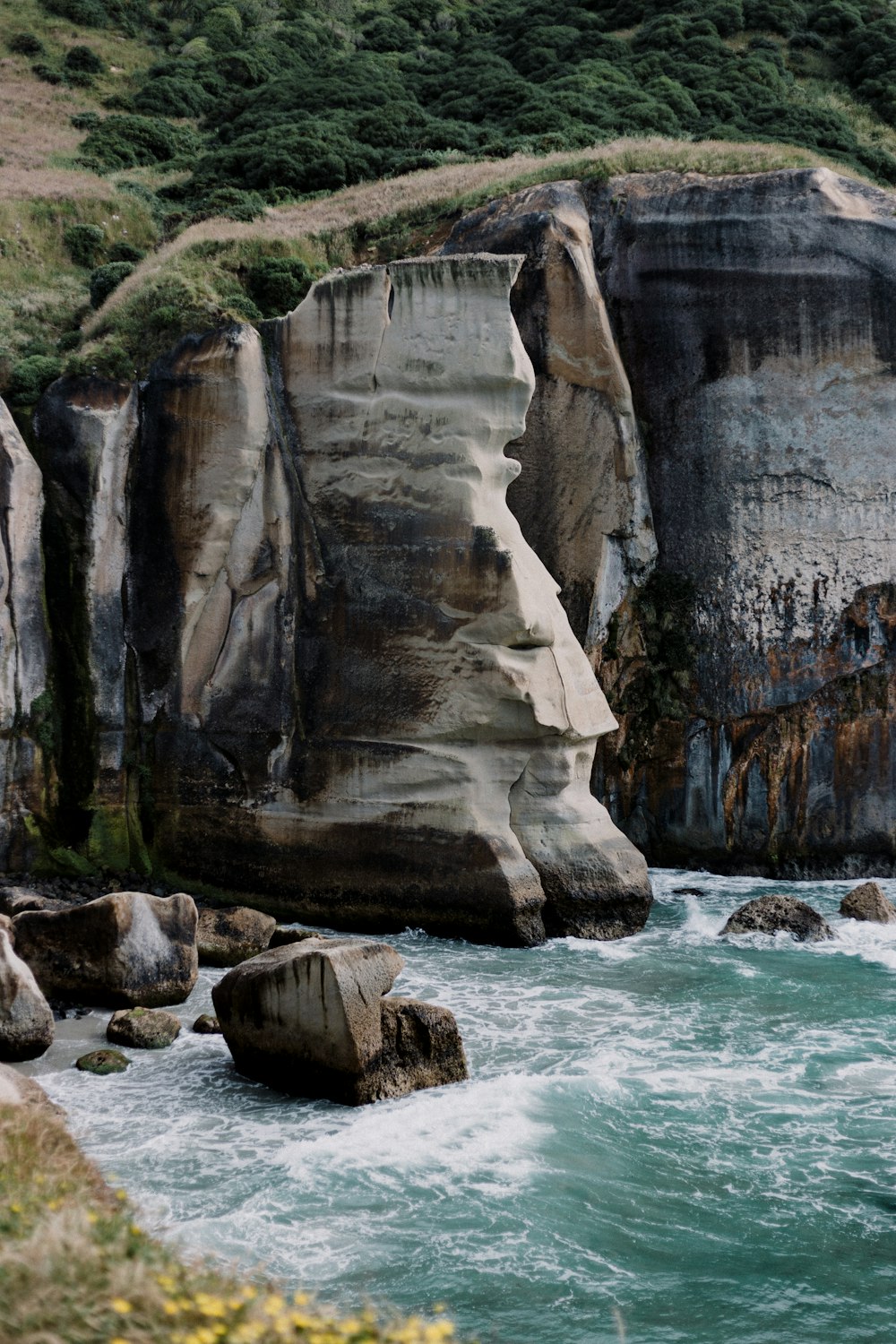 water crashing on rock formation beside cliff