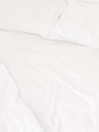 A neatly arranged bed with white sheets and pillows, conveying a sense of cleanliness and order. The fabric appears soft and inviting, suggesting comfort and relaxation.