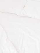 A neatly arranged bed with white sheets and pillows, conveying a sense of cleanliness and order. The fabric appears soft and inviting, suggesting comfort and relaxation.