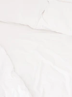 Close-up of a neatly made bed with crisp white linens and decorative pillows