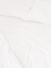 Close-up of a neatly made bed with crisp white linens and decorative pillows
