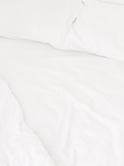 A neatly arranged bed with white sheets and pillows, conveying a sense of cleanliness and order. The fabric appears soft and inviting, suggesting comfort and relaxation.
