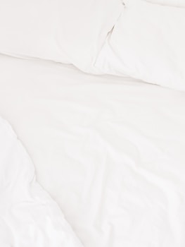 a close up of a bed with white sheets and pillows