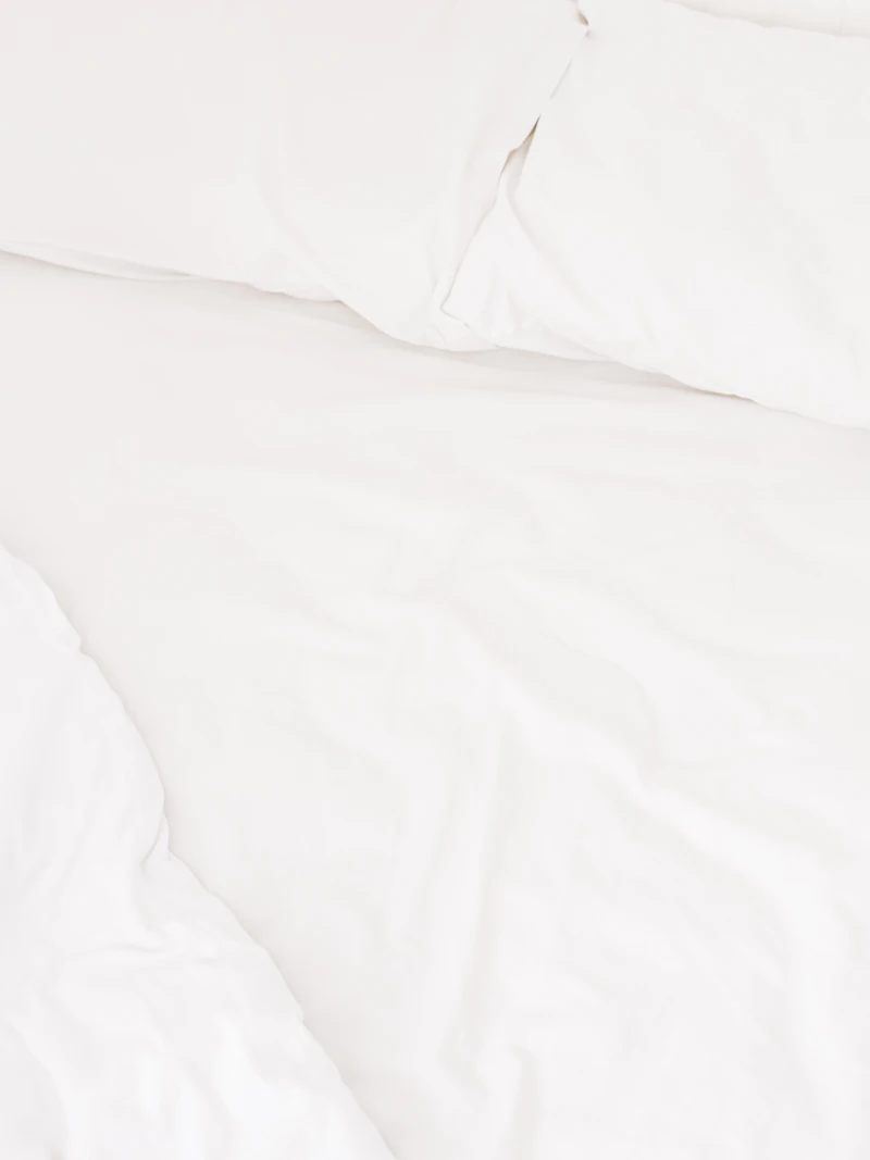 Clean white bedding and pillows on a made bed
