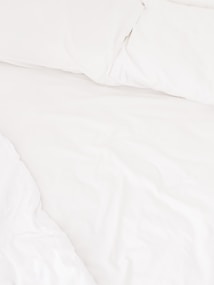 A neatly arranged bed with white sheets and pillows, conveying a sense of cleanliness and order. The fabric appears soft and inviting, suggesting comfort and relaxation.