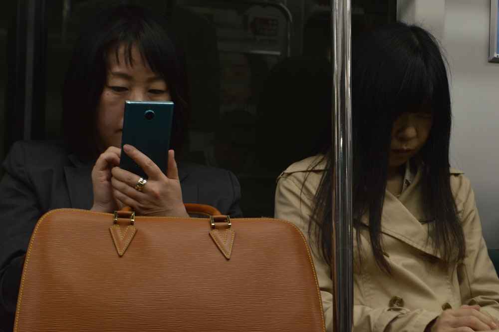 woman in train sits beside woman in beige coat