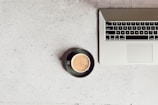 A close-up of a laptop with a coffee cup beside it on a desk.
