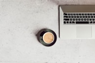 A laptop on a desk with a coffee cup beside it.