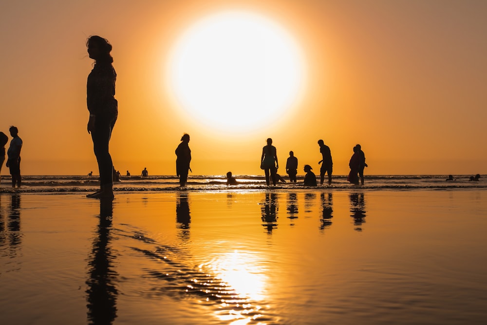 Silueta de la gente en la orilla durante la puesta del sol