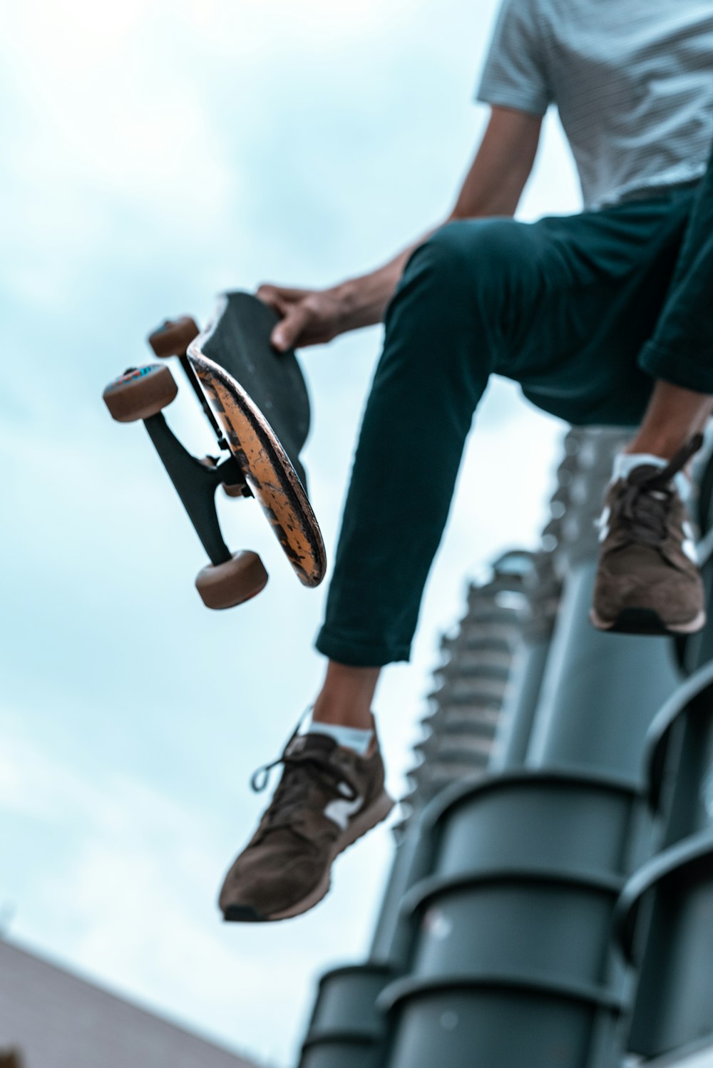 pessoa segurando skate preto enquanto pula em foto de visão de baixo ângulo