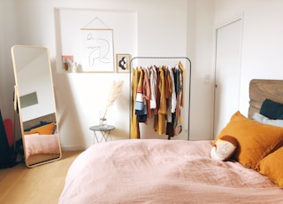 hanging clothes on rack near bed and door