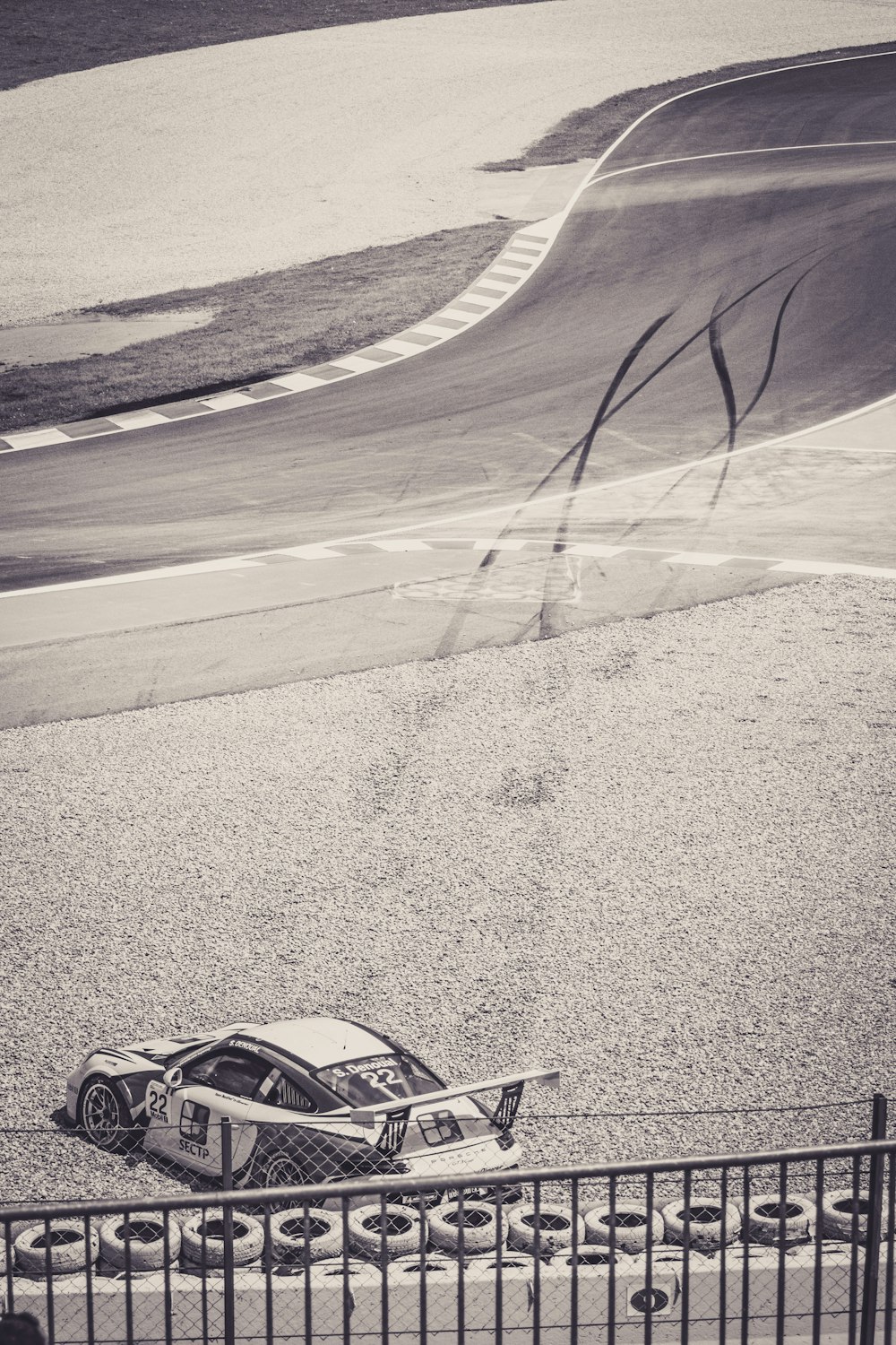 greyscale photo of racing car beside circuit road