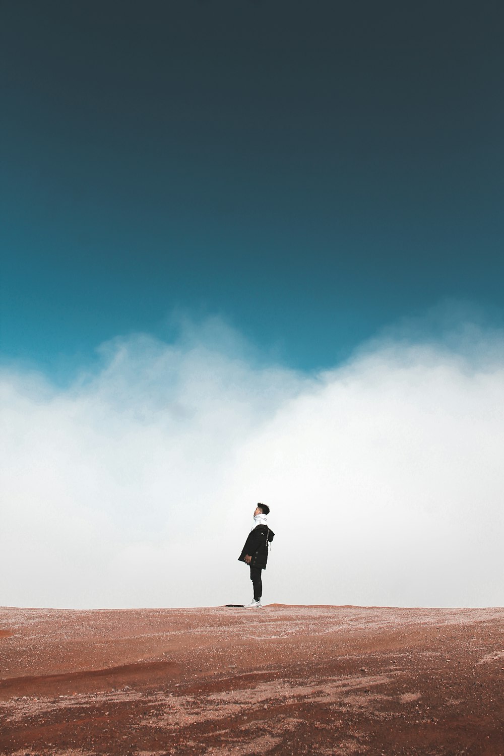 man standing on sand under clear blue sky