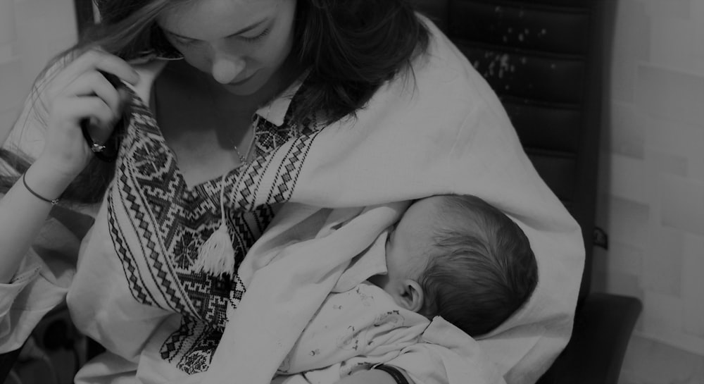 greyscale photo of woman carrying baby