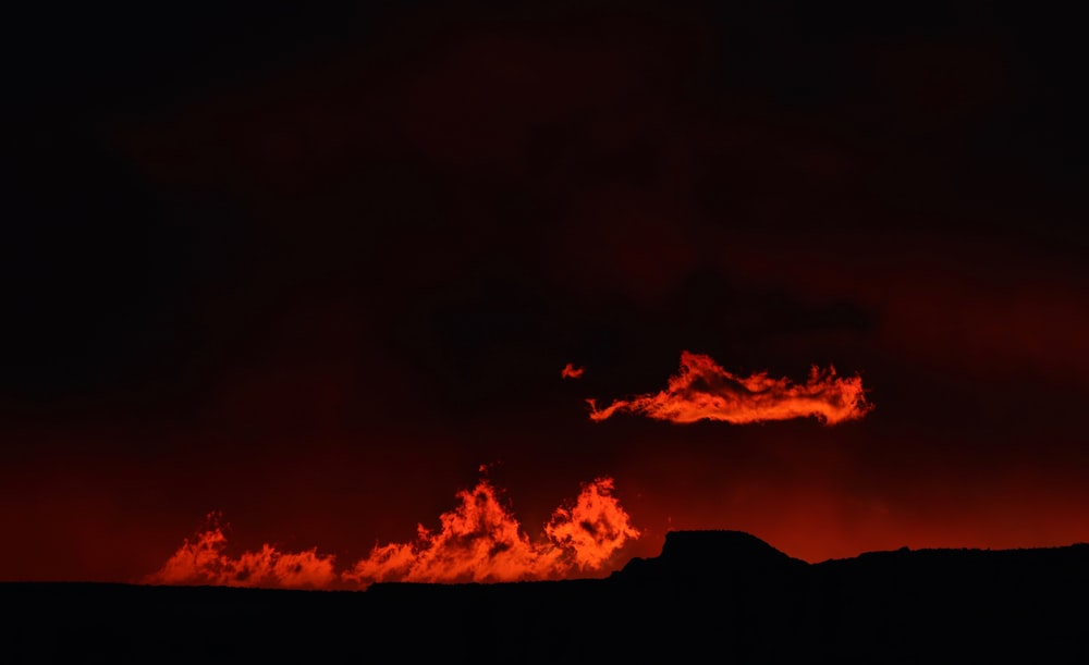 crimson clouds over silhouette of hills