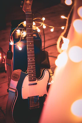A candid photo of Kentenfromlucca playing guitar in a cozy studio filled with warm lighting and vintage instruments.