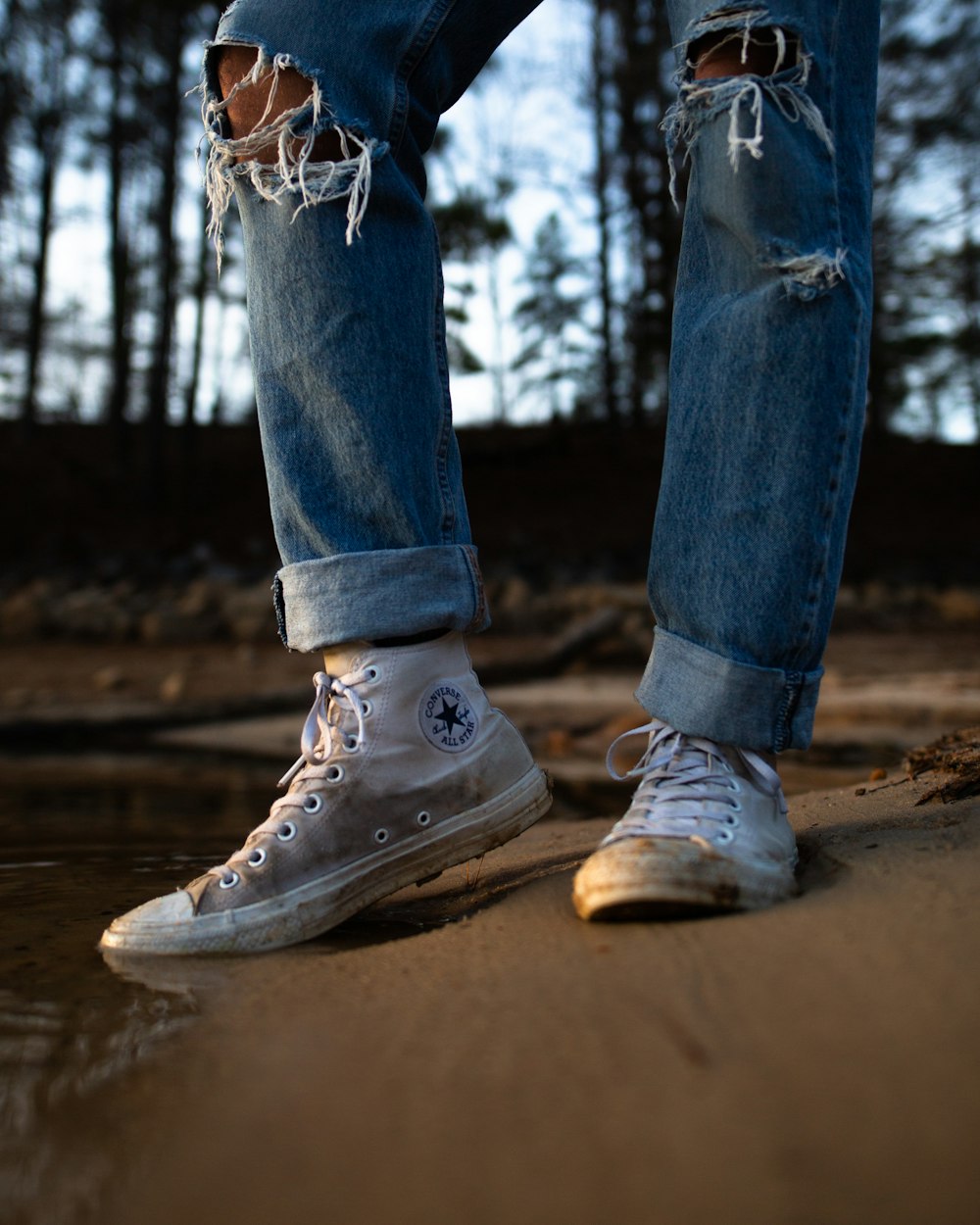 Foto Persona con vaqueros azules hechos jirones y zapatillas Converse blancas – Zapato gratis en Unsplash