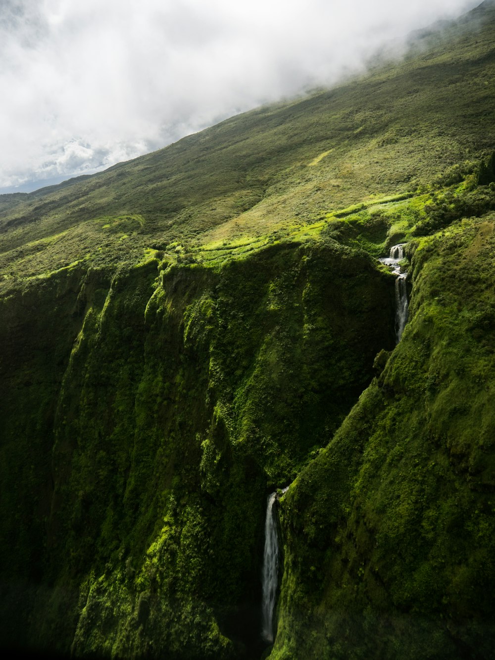 green grass field with waterfall during daytime