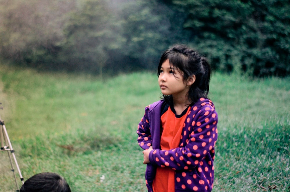 shallow focus photo of girl in purple and pink polka-dot jacket