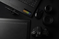 A creative flat lay of Alejandro’s favorite tools: notebooks, pens, and a camera, all set against a dark background.