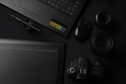 Black lapto and black camera on desk