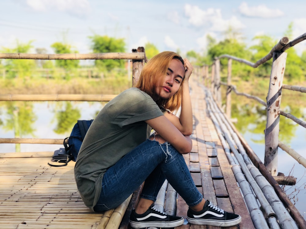 woman sitting on wooden bridge