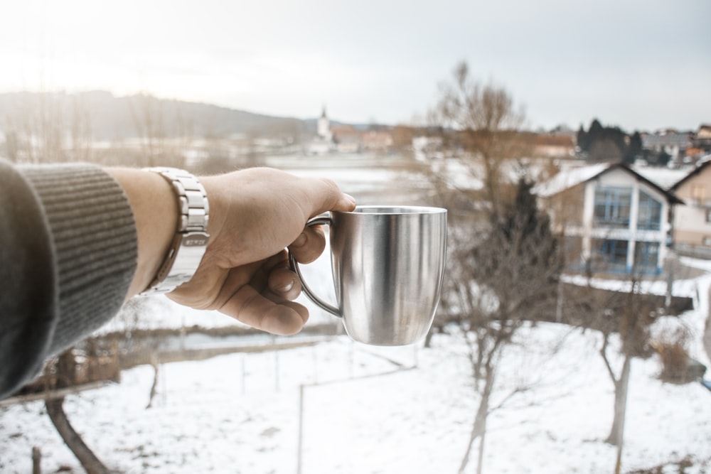 person holding silver metal mug