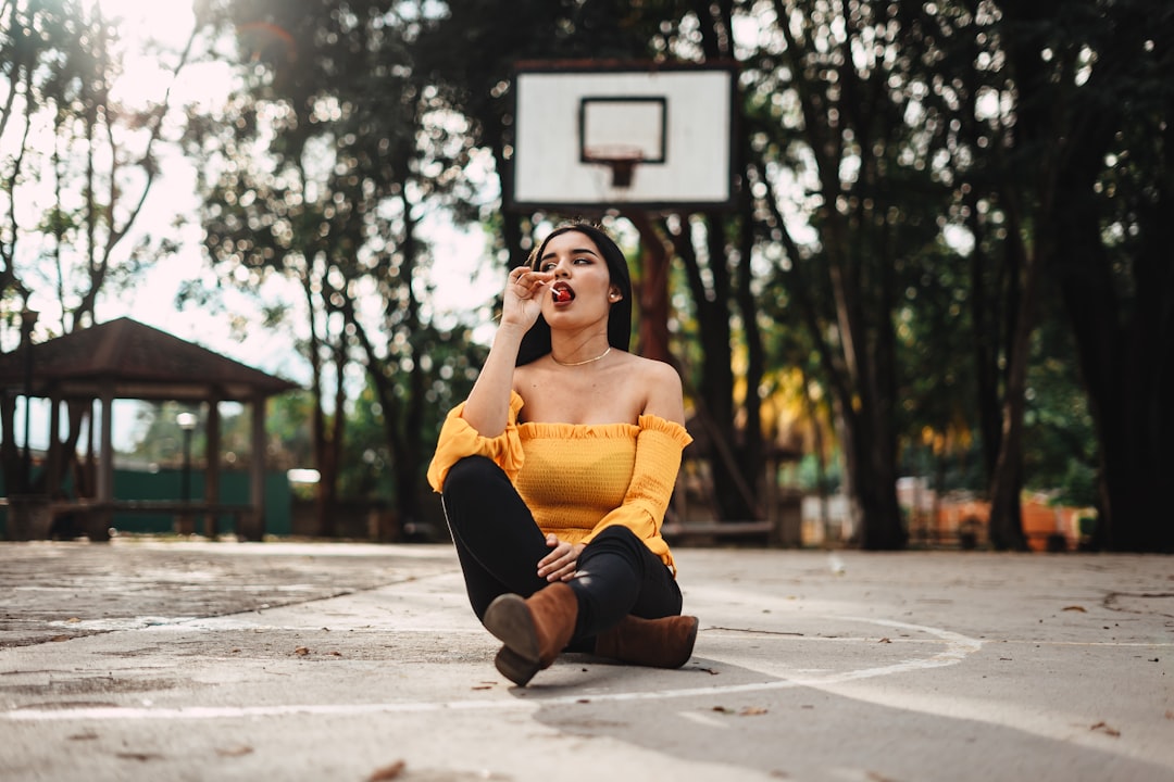 woman sitting on basketball court during daytime