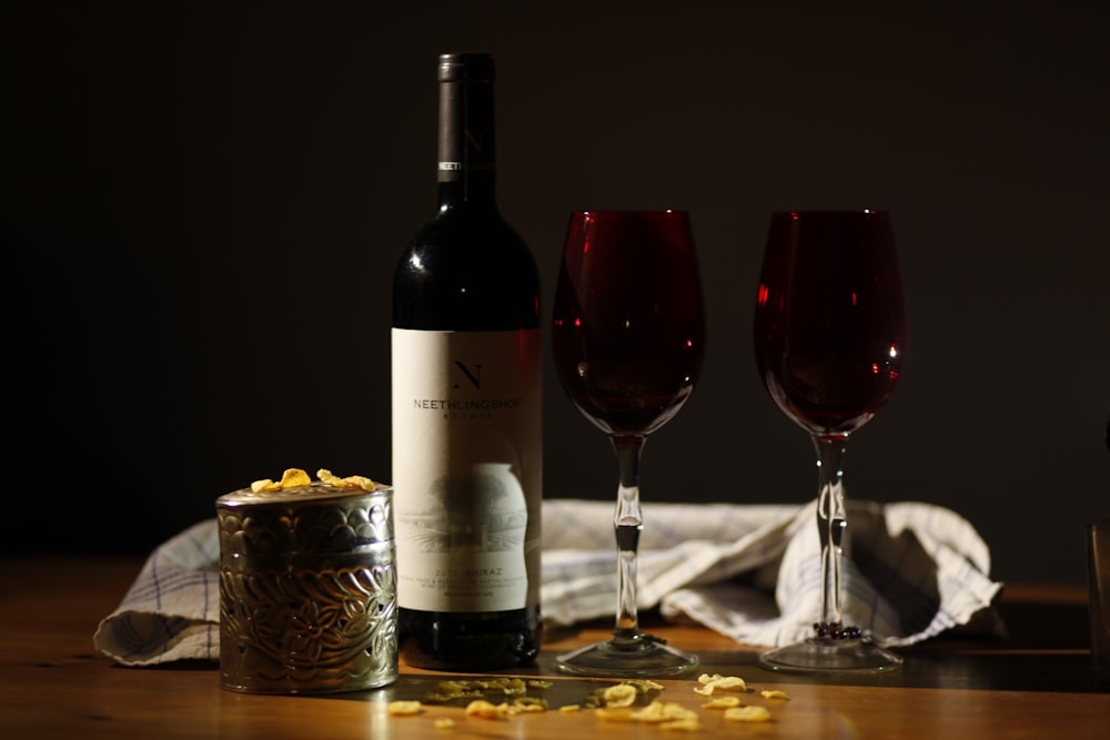 테이블 위의 두 개의 빨간 잔 옆에 와인 병