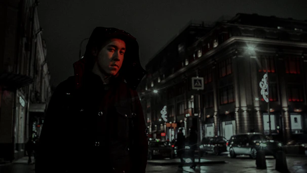 Volunteers in black hoodies handing out meals to people on a dimly lit urban street at night.