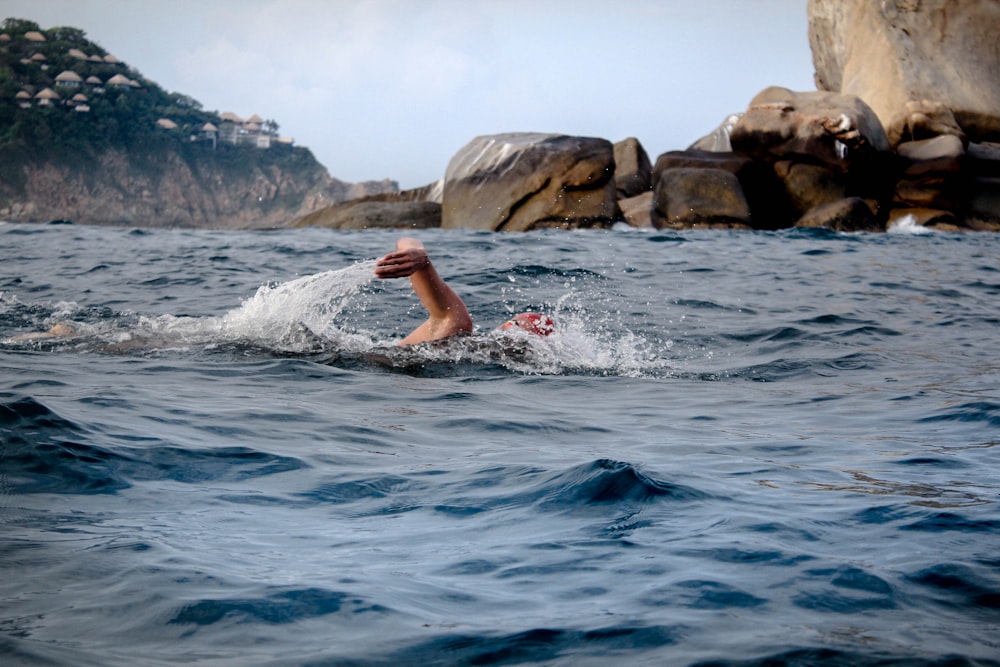 person swimming across brown rocks