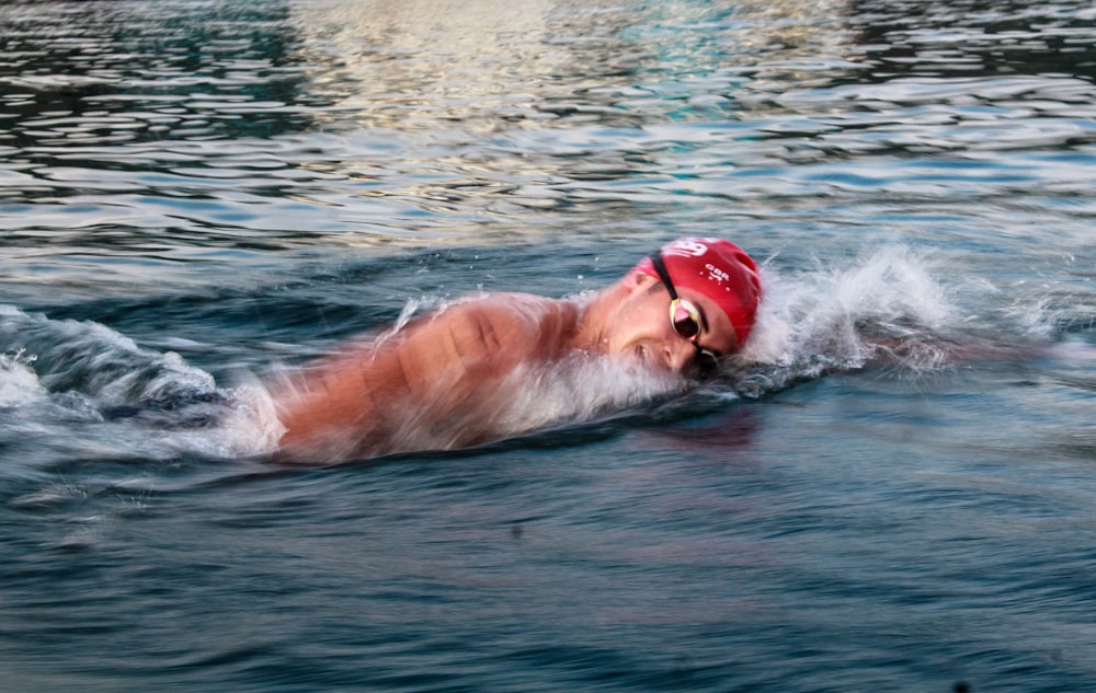man swimming on body of water during daytime