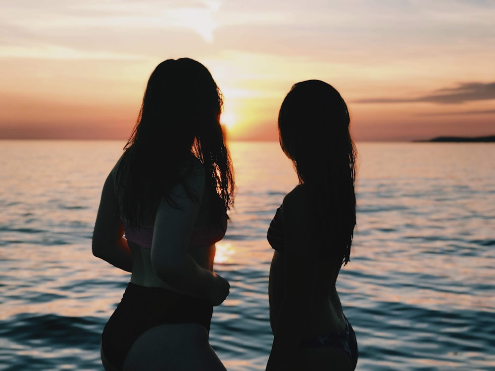 silhouette of two women looking at sunset