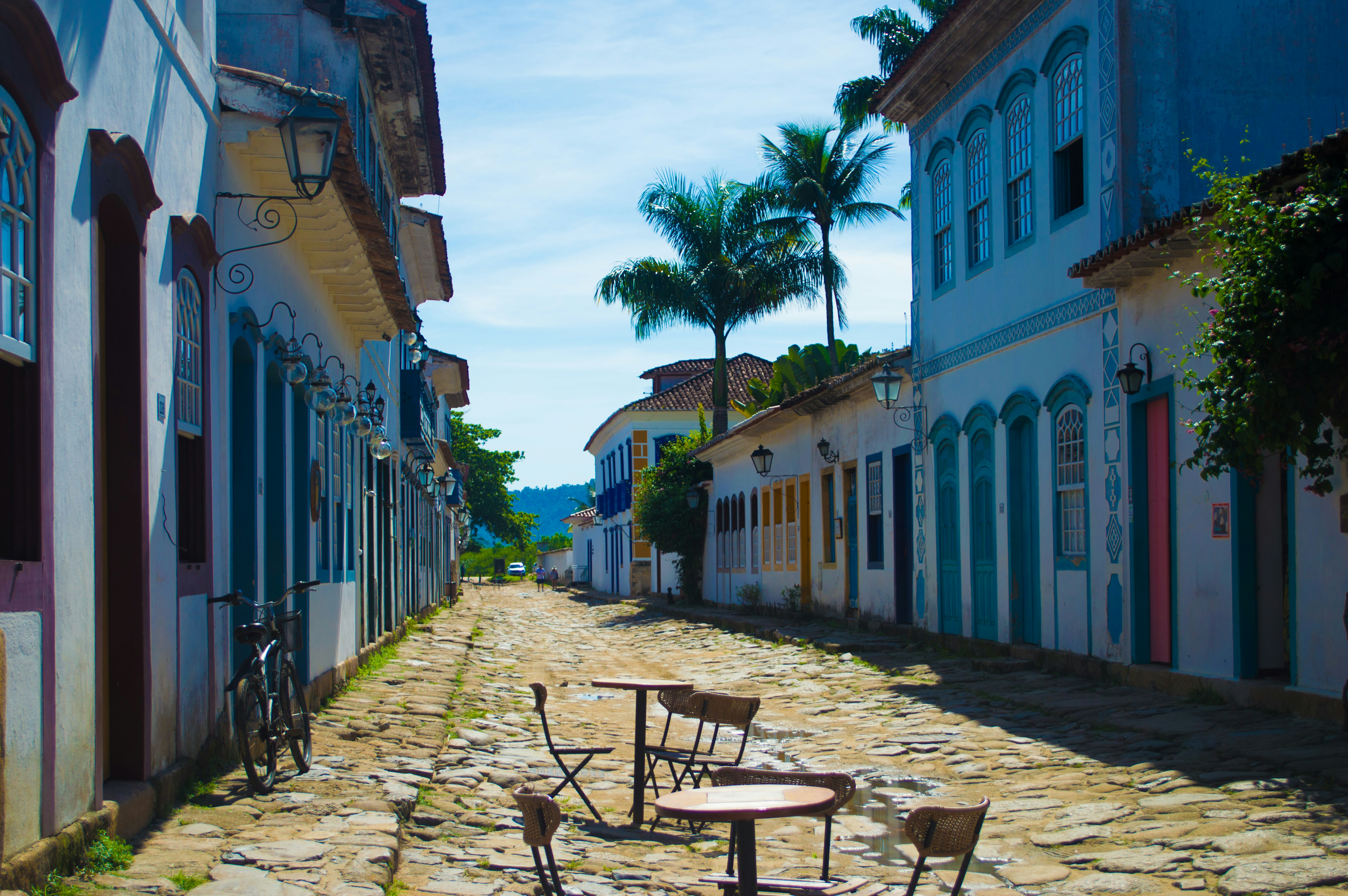 Calle colonial de Cartagena con casas amarillas y balcones floridos, palmeras, cielo azul caribeño