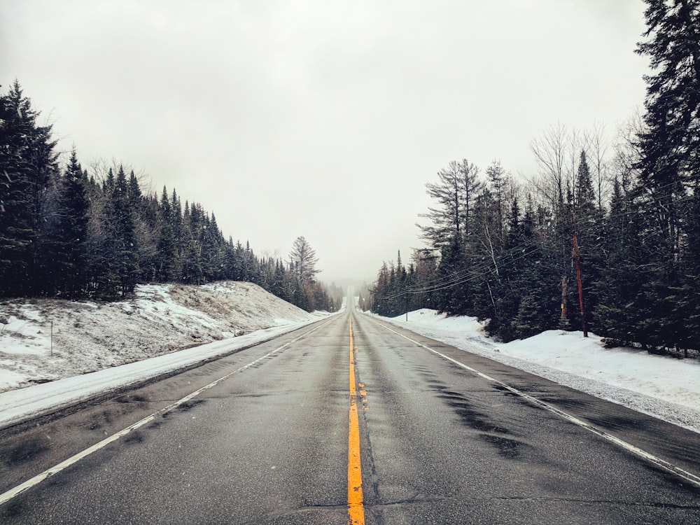 empty road with snow covered fields on the side