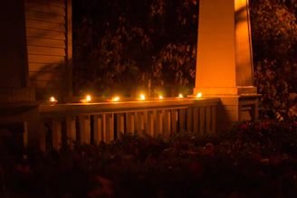A candle glowing softly on a rustic wooden porch overlooking rolling Kentucky hills at sunset.