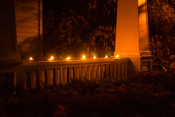 A candle glowing softly on a rustic wooden porch overlooking rolling Kentucky hills at sunset.