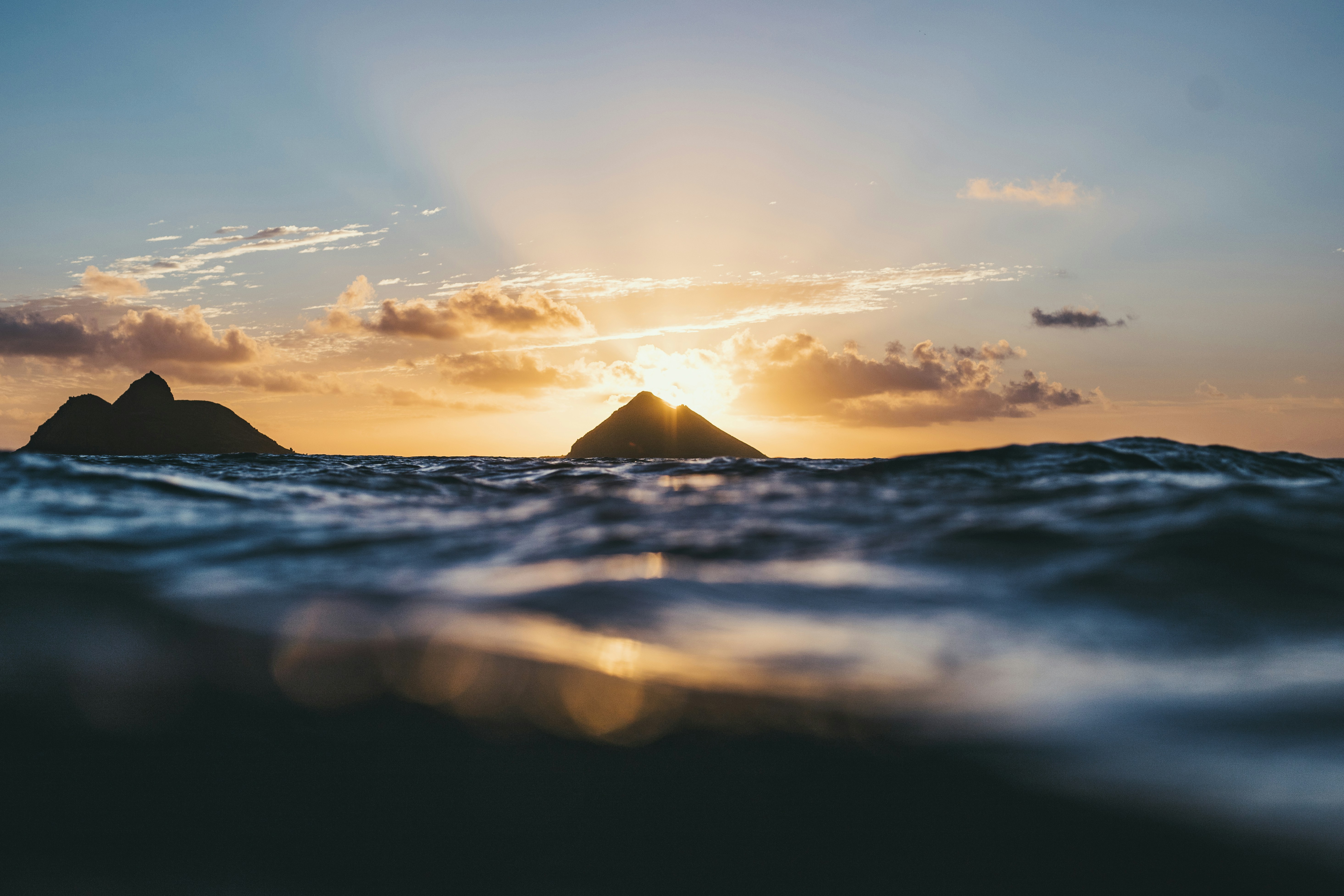 We arrived at Lanikai Beach moments before sunrise. My aim was to get the sun rising between the two islands out the back. Though, once I had been swimming for 15 minutes or more out the back - I realised that I would still have to swim much further out to get this angle, and I realised it might not even look as good as I imagined. So I opted for the slightly safer option of shooting just a few hundred meters from shore (which was still a fair way out, and was a little eerie with the strong current sweeping up the beach). I waited for the sun to rise to the top of the right island & took this!