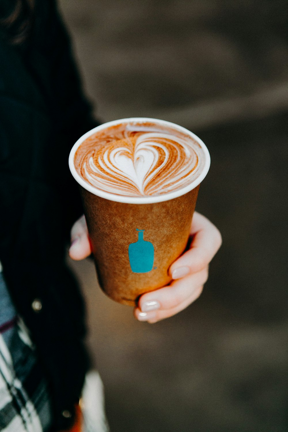 person holding cup with brown liquid