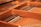 A close-up view of the inside of a piano, showcasing the strings and hammers. The warm wood tones and metallic strings are prominently featured, highlighting the intricate craftsmanship of the instrument.