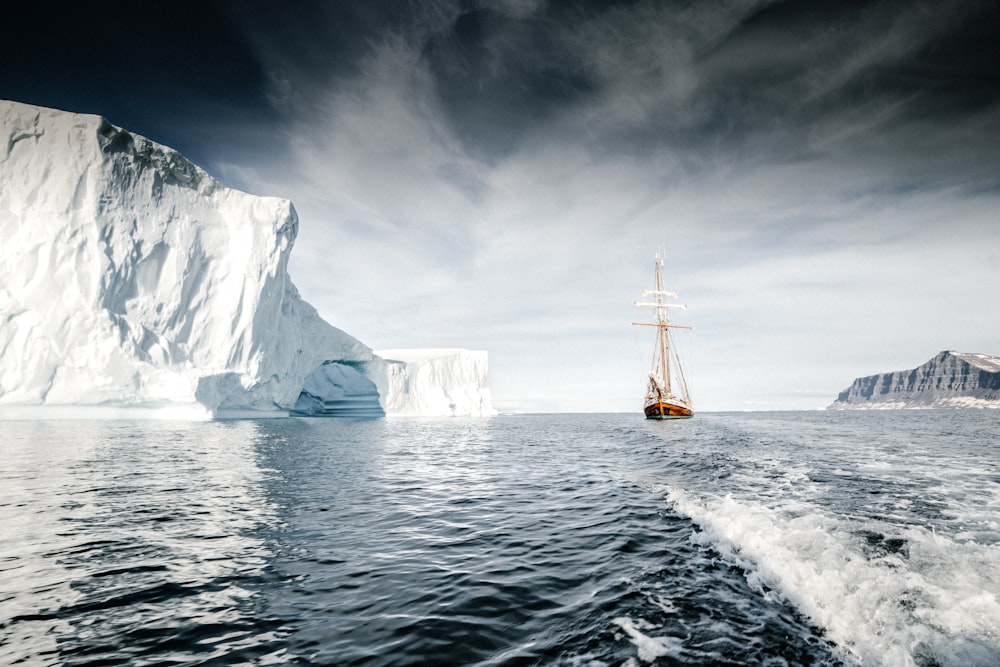 Braunes hölzernes Segelschiff, das auf dem Meer in der Nähe des Eisbergs segelt