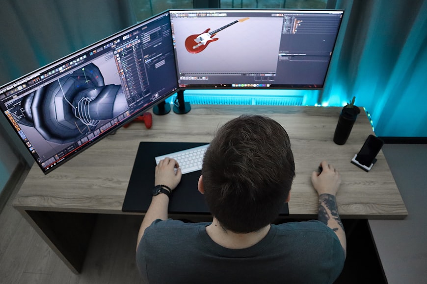 Animator create a 3d guitar with a working environment with 2 monitors and have a tattoo on right hand.