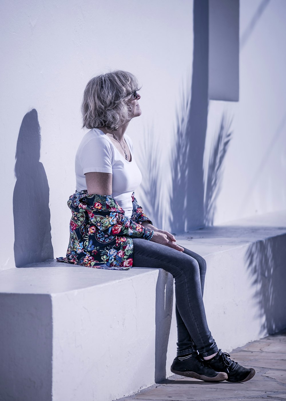 woman in white shirt and skinny jeans sitting on concrete seat