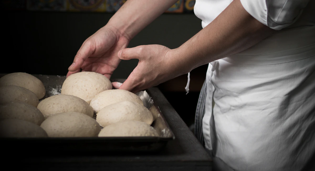 Hands stretching dough across a flour-dusted bench